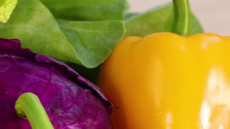 a colorful display of yellow peppers, purple cabbage, cauliflower, potatoes, and tomatoes on a light background.