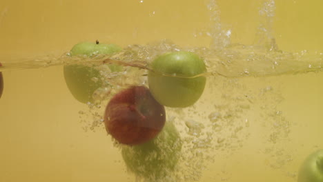 tiro de un montón de manzanas con diferentes colores caídos en el agua