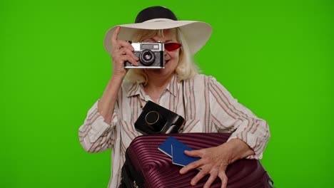 senior woman tourist photographer taking photos on retro camera and smiling on chroma key background