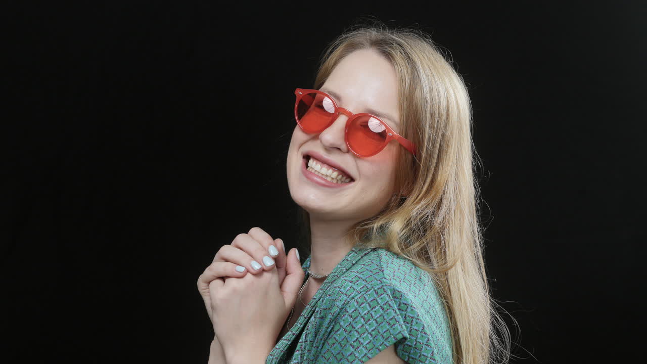 happy female with red sunglasses on black background