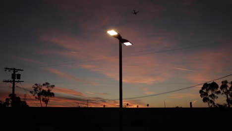 puesta de sol urbana, avión pasando por cables telefónicos y autopista en cámara lenta, hermosa