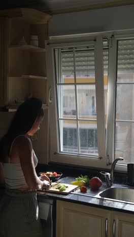 woman preparing a salad in a kitchen with a view