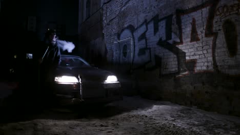 man smoking in a snowy alleyway at night