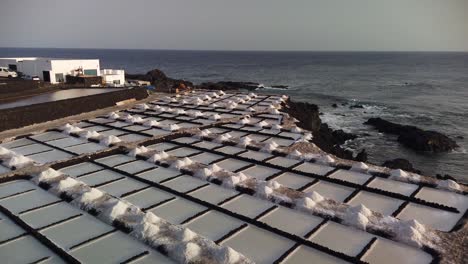 a dinamic panning shot of saltworks beside the sea in a rocky coast at the evening