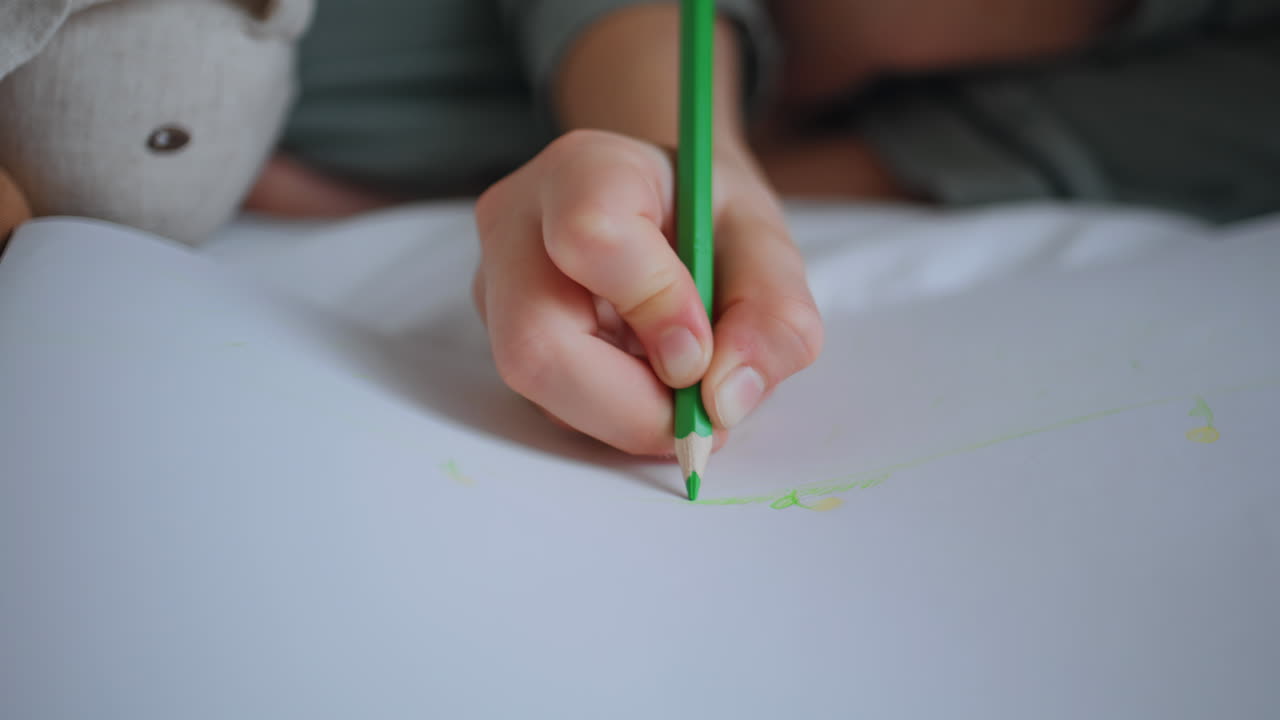 Unknown kid drawing album at home closeup. Child holding pencil enjoying art