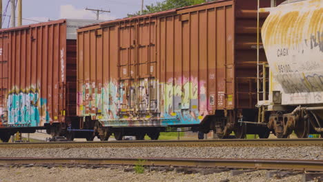 Mit-Graffiti-Bedeckte-Eisenbahnwaggons,-Die-über-Die-Bahngleise-Rollen