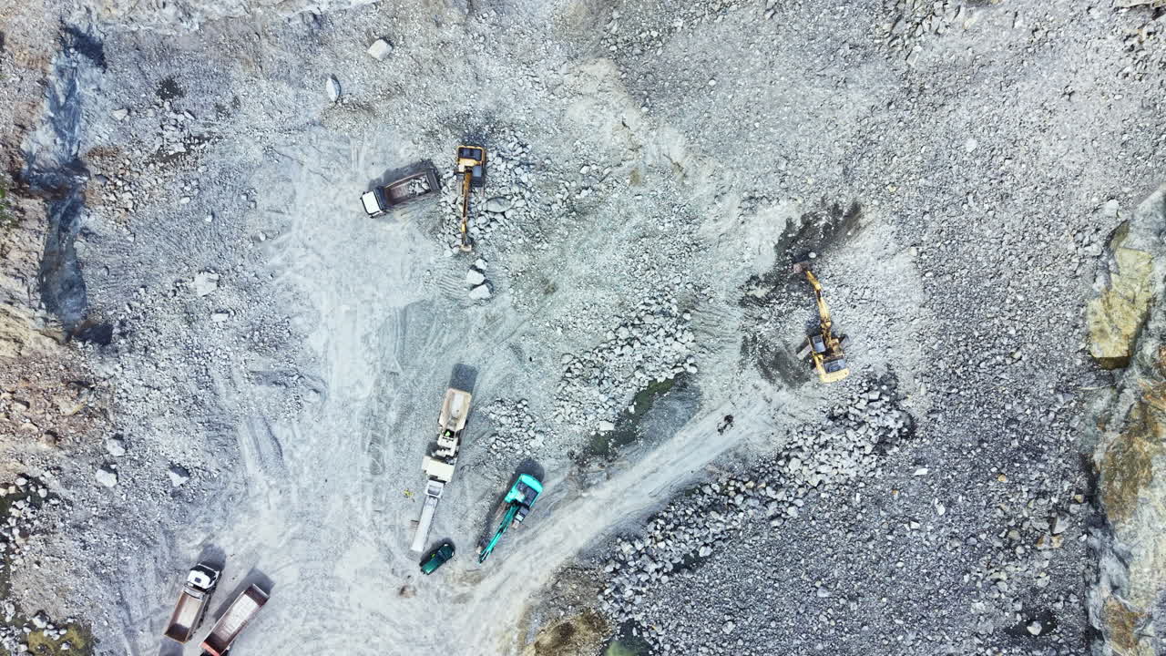 Granite quarry site in operation with heavy machinery and vehicles working on stone extraction and processing activities during daylight hours