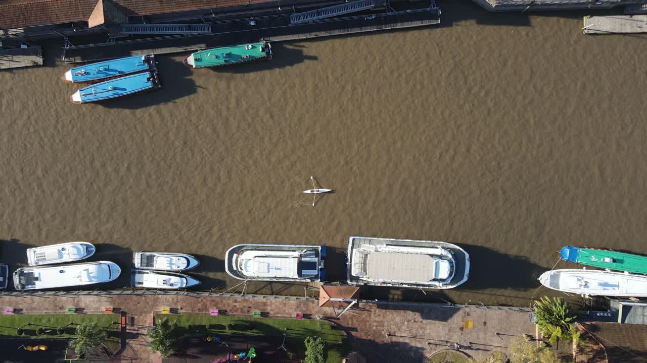 Cinematic drone shot of people in boat kayaking on river lujan in Tigre during sunny day in summer