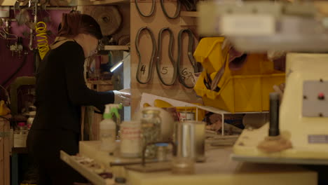 Female-shoemaker-polishing-leather-sole-on-industrial-machine-in-the-back-of-workshop