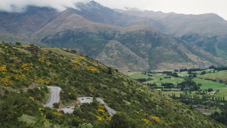 Cars-winding-on-scenic-switchback-road-with-mountains-in-background