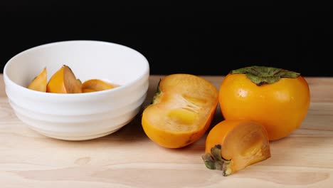 persimmon slices drop into a white bowl