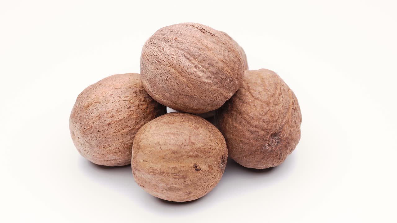 nuez moscada (myristica fragrans), entera, aislada en una rotación de bucle blanco sin costuras