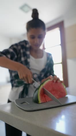 adolescente cortando sandía en una cocina
