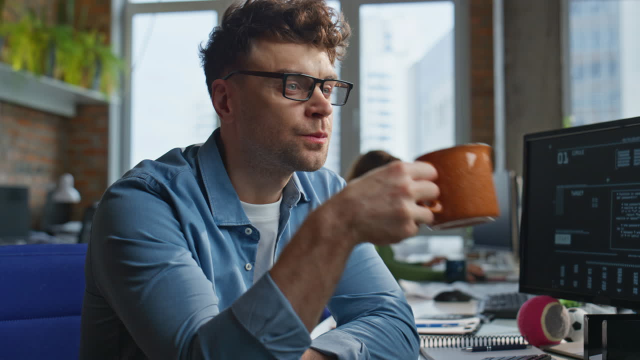Office worker drinking coffee in agency closeup. Businessman looking monitor