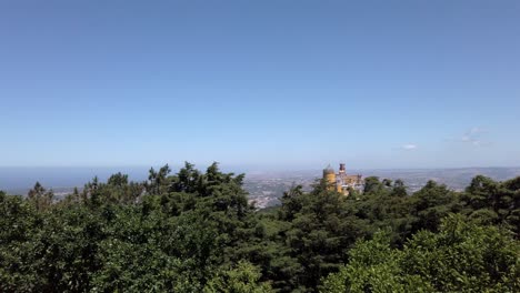 Overlooking-colorful-Pena-Palace-in-Portugal-rising-above-trees-on-windy-clear-day