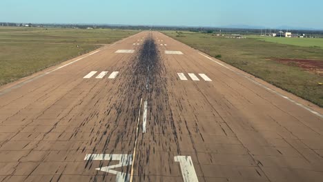 an immersive pilot’s view of a real time approach and alanding on a isolated african airport worn-out runway under a blue sky