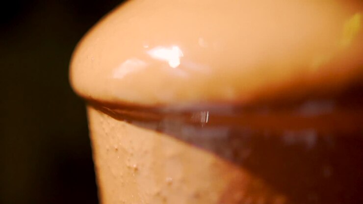 Primo piano di cioccolato fuso caldo che scende a cascata dalla fontana, un dolce dessert caldo che cola in modo appetitoso dalla fontana
