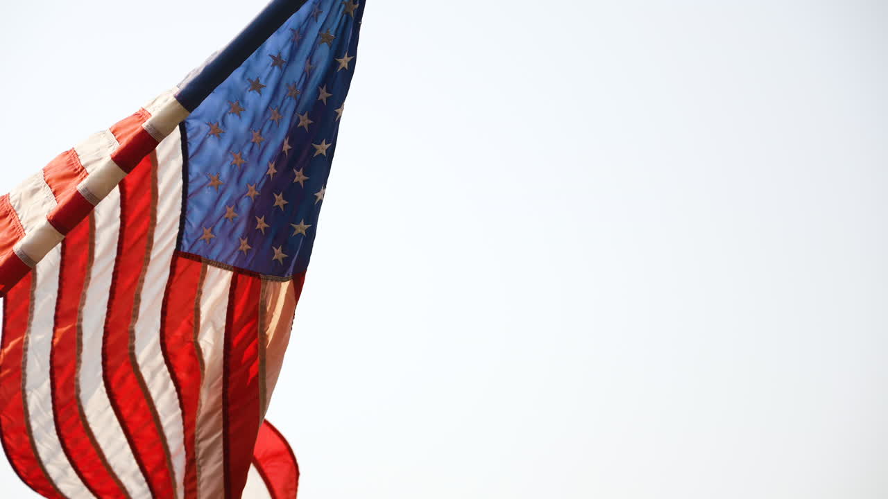 Slow motion shot of an American flag flying in the wind on a flag pole
