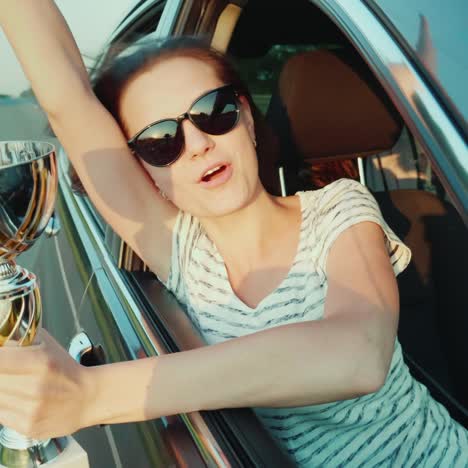 a young woman with a winner's cup in her hand looks out the window of a moving car, emotionally rejoicing