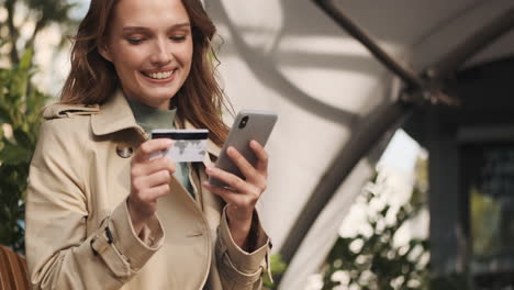 estudiante caucásica haciendo compras en línea en el teléfono inteligente al aire libre.