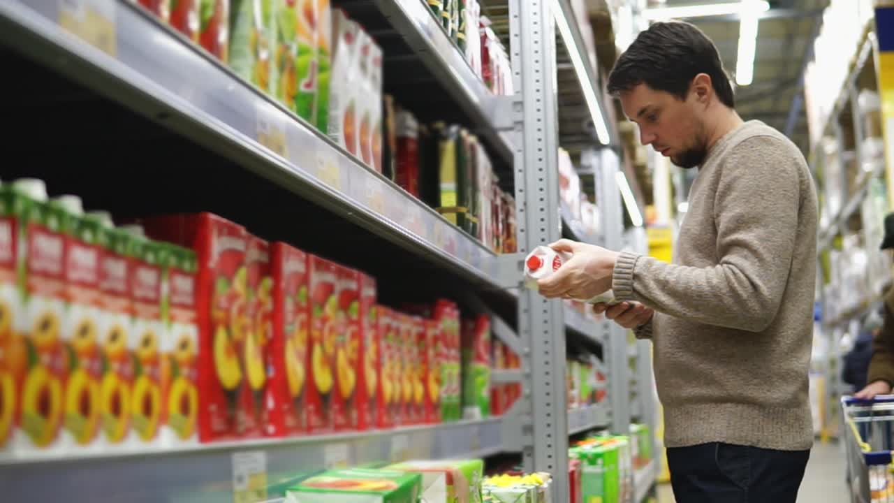 한 남자가 식료품 가게에서 주스를 구입하고 있다