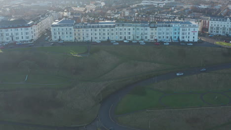drone shot of a row of terraced victorian style homes on a hill with parked cars.