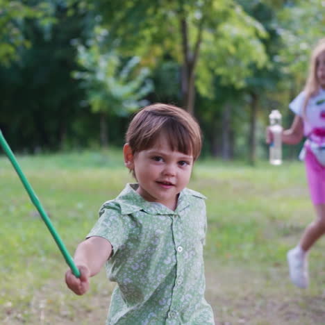 little children playing with soap bubbles in nature. pretty girl blowing colorful bubbles and small cute boy trying to catch them in the park.