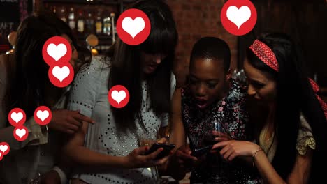 vários ícones de coração se movendo contra um grupo de amigas usando um smartphone