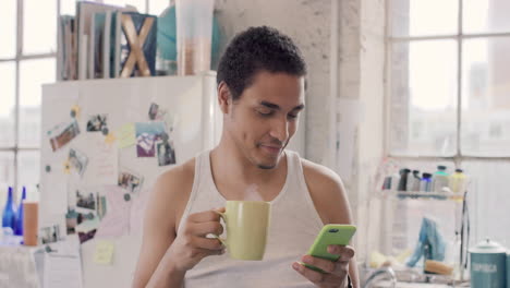 Joven-Estudiante-Usando-Un-Teléfono-Inteligente-En-Casa-Por-La-Mañana-Tomando-Café