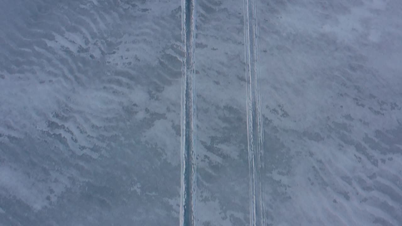 얼어붙은 호수의 슬러시 눈 속에서 스노모빌 트랙 위로 거꾸로 날아가는 공중 탑다운