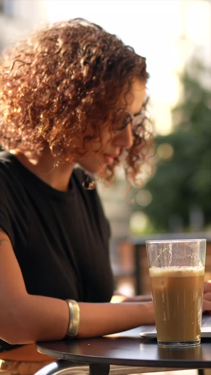 Woman with Curly Hair and Sunglasses at Outdoor Cafe