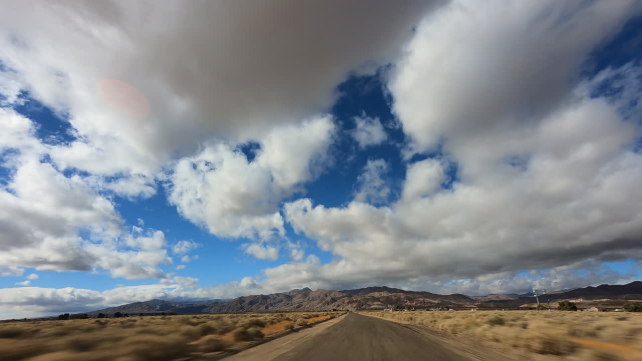 conduciendo a través del desierto de mojave con una sobrecarga de cloudscape dramática - hiperlapso