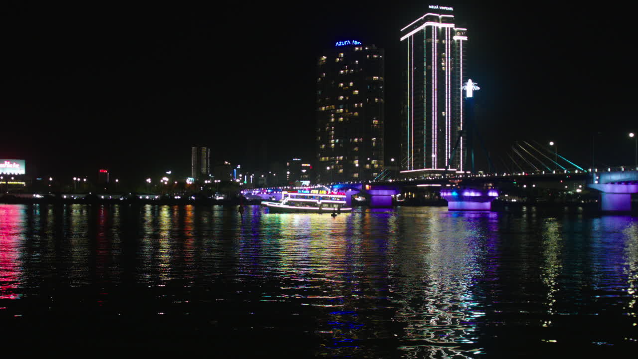 vista nocturna del puente tran thi ly sobre el río han y crucero navegando en la ciudad de da nang de vietnam iluminada con luces y edificios en el horizonte como telón de fondo