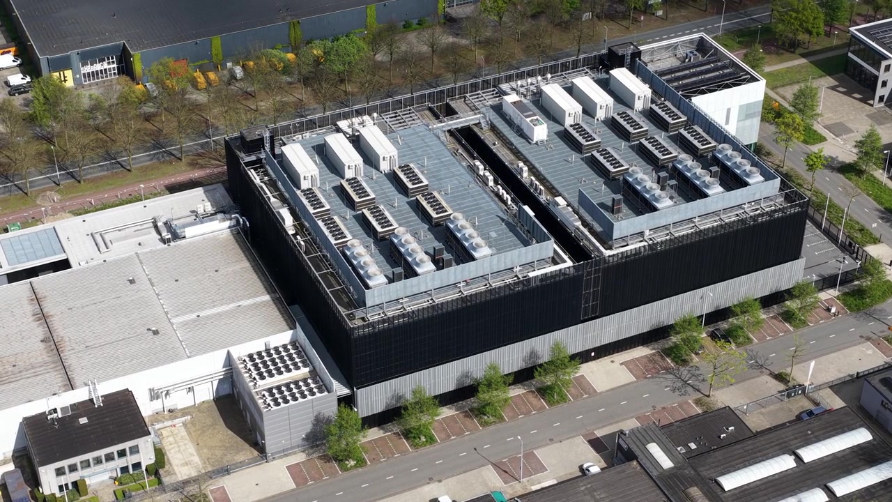 Modern data center building housing servers for cloud computing and big data storage, featuring numerous cooling units and solar panels on the rooftop for efficient and sustainable operation