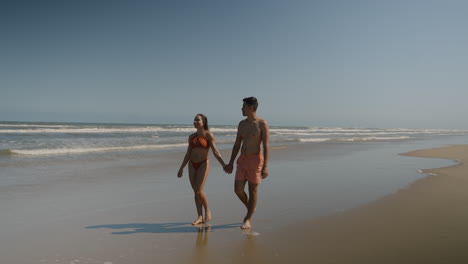 una pareja linda caminando por la playa.