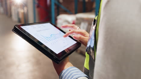 mujer trabajando en un almacén con una tableta, analizando datos y gráficos
