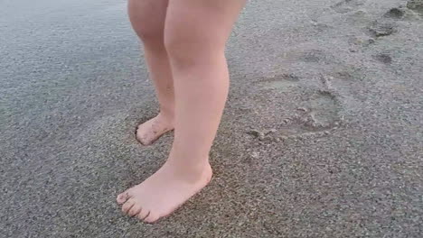 baby walking on sandy beach and waves splashing on legs