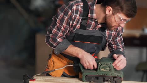 portrait-of-a-young-carpenter-working-with-a-belt-sander