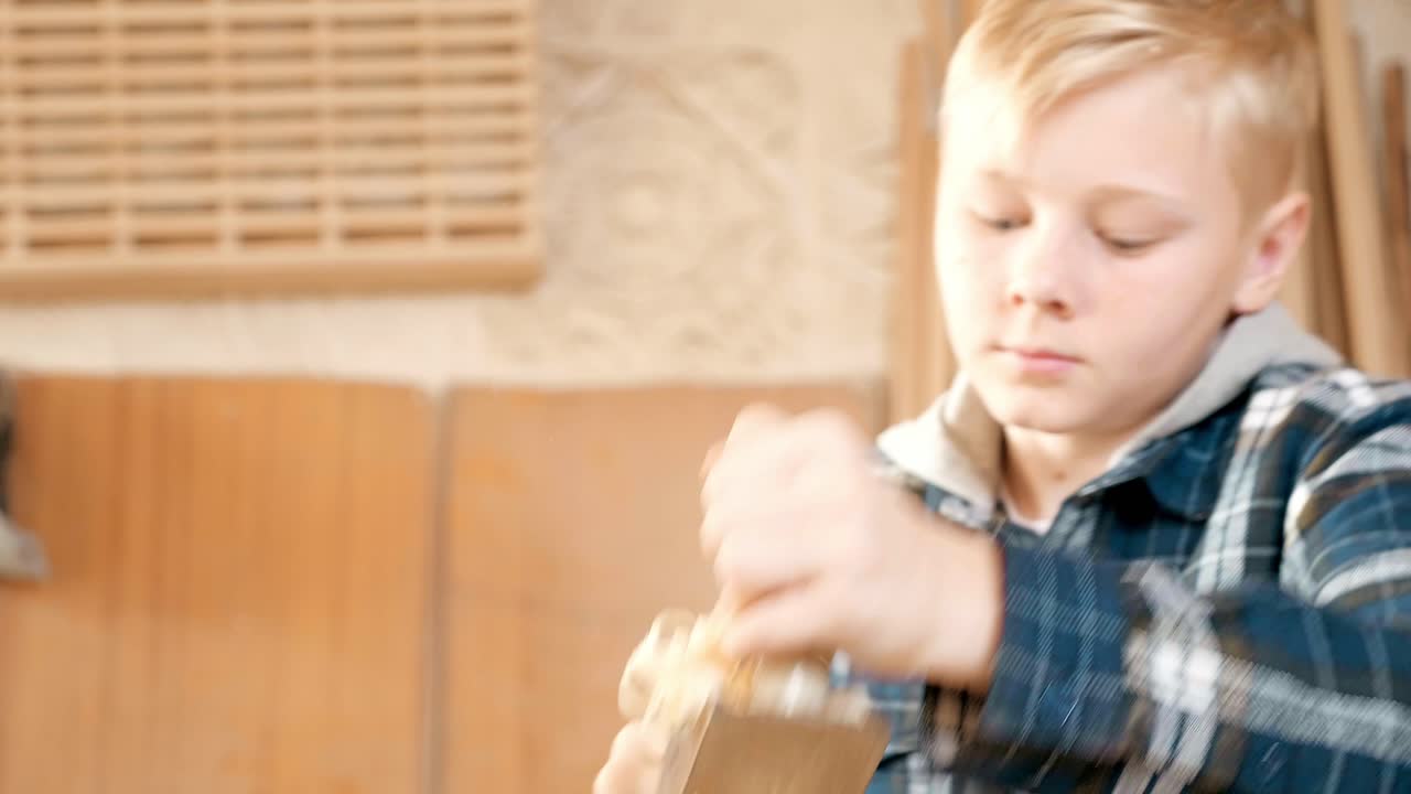 Young boy learning woodworking in a workshop