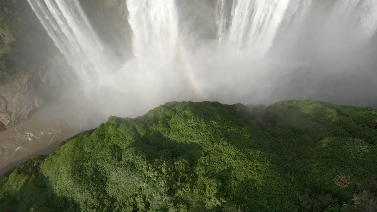 el arco iris aparece en la niebla de la cascada mientras el agua cae en la selva de méxico, aérea