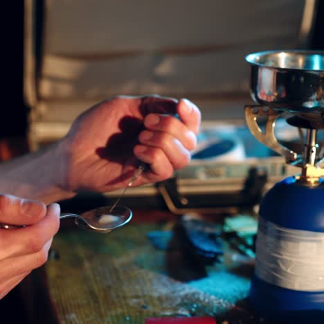 male junkie hand preparing heroin dose by using spoon and cigarette lighter for melting, syringe for injection. hard drug overdose and addiction concept