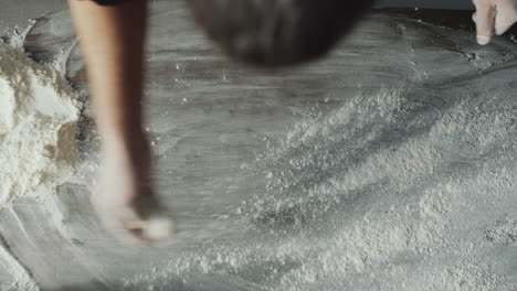 man sprinkling flour over table