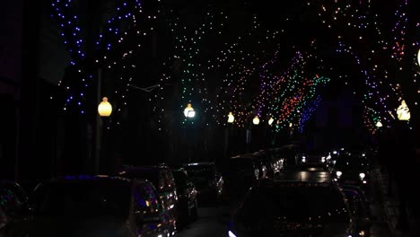 various cars driving at night through downtown city streets with decorated trees for christmas festive season bright colorful lights madeira island celebrating xmas graded reveal tilt hd background