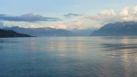 flying low over lake léman with sunset light over the alps in the background, waves and reflections on the water lutry - switzerland