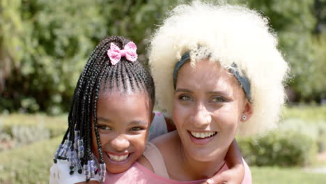 African-American-child-with-braided-hair-hugs-a-young-biracial-woman-with-curly-hair