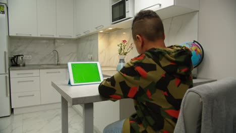 kid scrolling chroma key green screen on digital tablet indoors