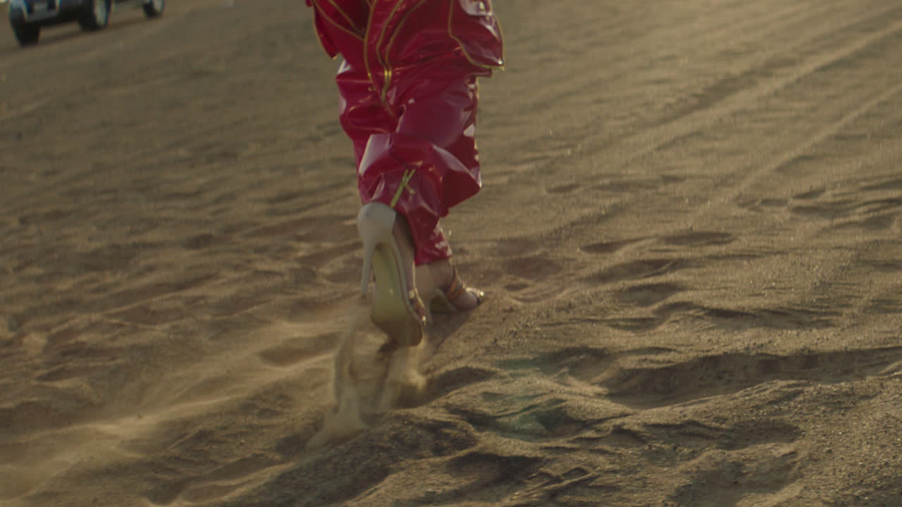 Low angle track shot of woman with high heels walking on sandy desert in Dubai
