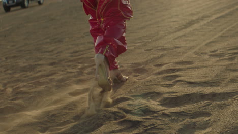 low angle track shot of woman with high heels walking on sandy desert in dubai