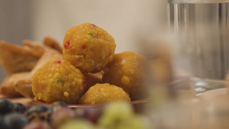 primo piano di laddoo e samosa sul tavolo della famiglia musulmana in casa per un pasto che celebra l'eid