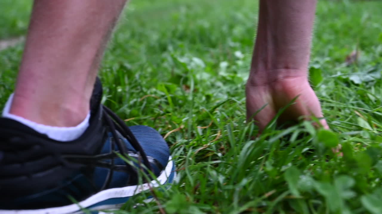 운동선수는 달리기 시작할 준비가 되어 있고, 잔디에 손을 얹고, 자연에서 운동을 합니다.